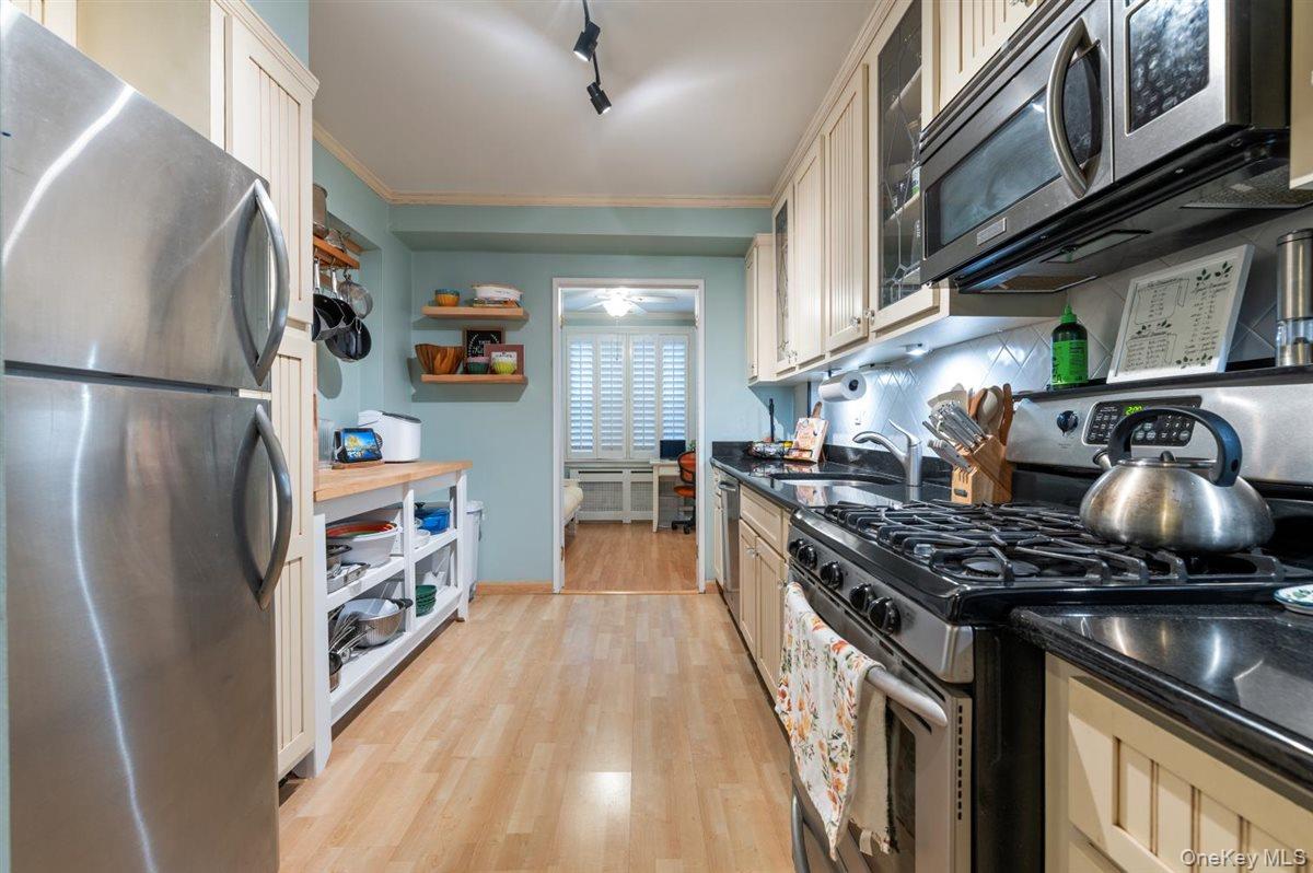 700 Shore Road, Unit 7Y Long Beach, NY 11561 - Photo 16 of 31 Kitchen with appliances with stainless steel finishes, light wood finished floors, open shelves, ornamental molding, and rail lighting