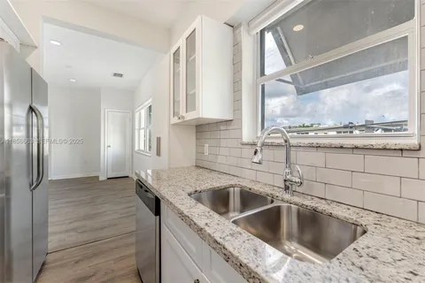 a kitchen with a sink granite counter tops and a view of living room