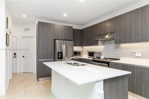 a kitchen with stainless steel appliances a sink a stove a refrigerator and cabinets