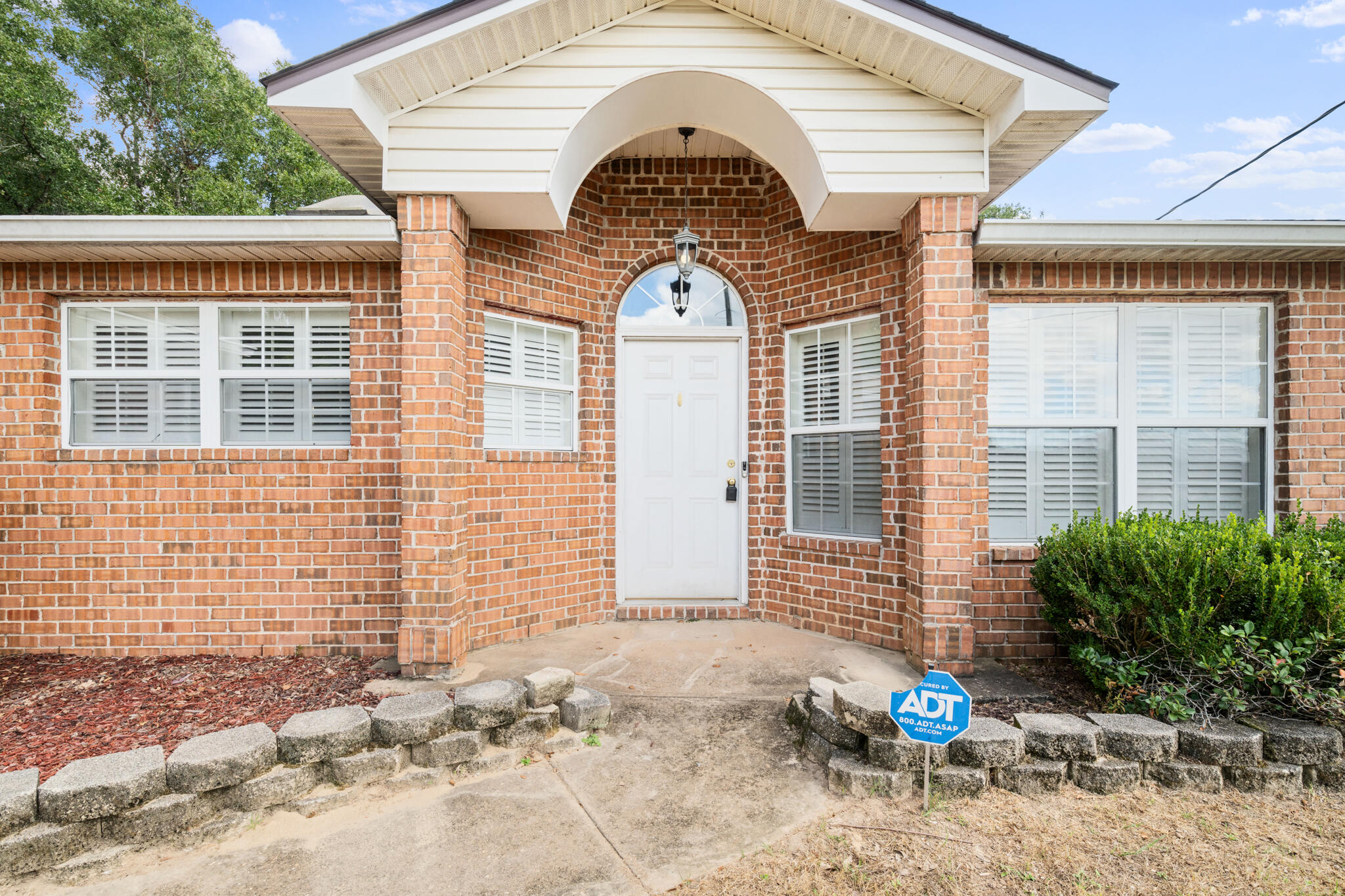 233 Lustan Drive Crestview, FL 32536 - Photo 4 of 22 a view of a brick house with potted plants