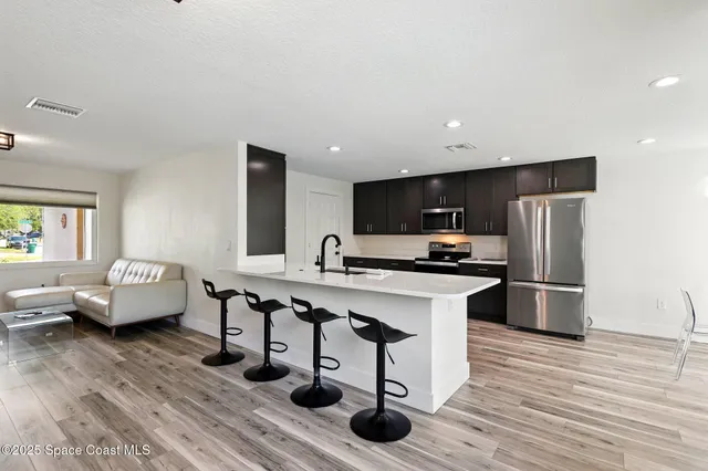 a kitchen with stainless steel appliances kitchen island hardwood floor sink and stove