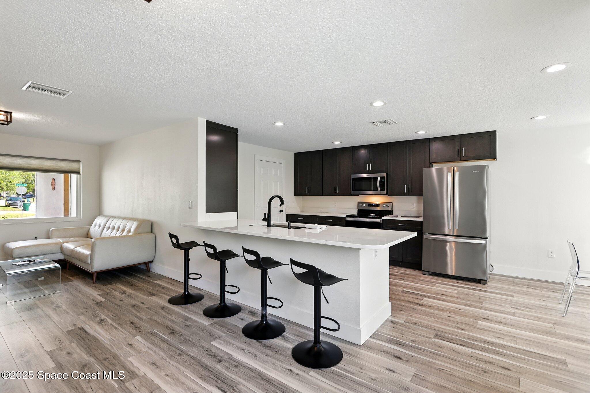 135 Richland Avenue Merritt Island, FL 32953 - Photo 15 of 24 a kitchen with stainless steel appliances kitchen island hardwood floor sink and stove