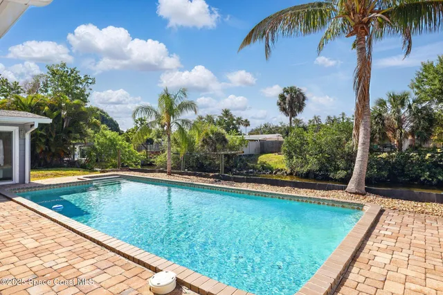 a view of swimming pool with a garden and a patio