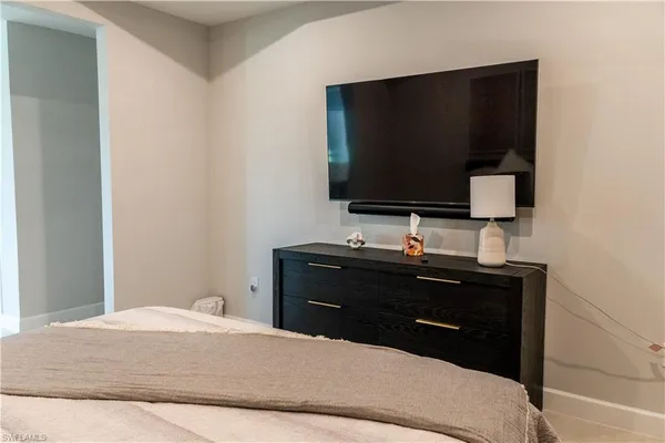 a bedroom with a bed and a flat tv screen on dresser