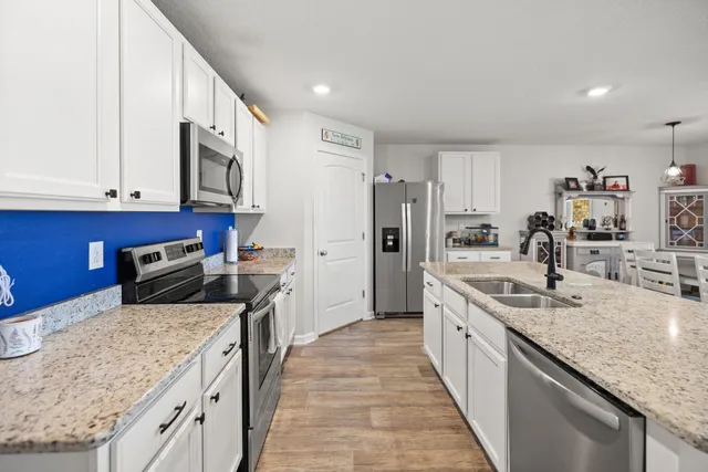 a kitchen with stainless steel appliances granite countertop a stove a sink and a microwave