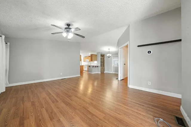 a view of an empty room with a window and wooden floor
