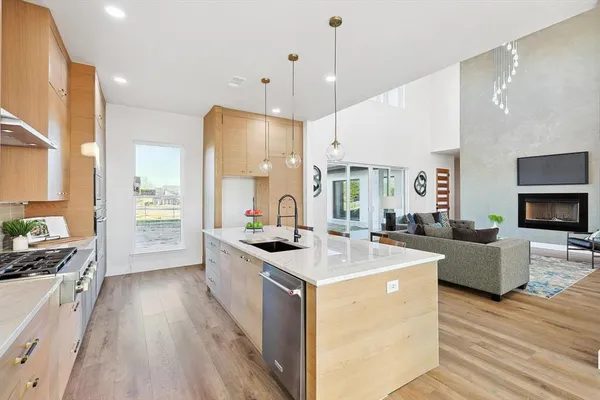 a large kitchen with stainless steel appliances a stove a sink dishwasher a oven and a dining table with wooden floor