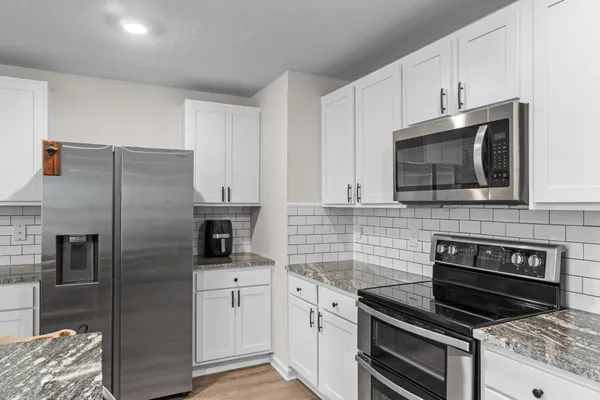 a kitchen with stainless steel appliances granite countertop a sink refrigerator and microwave