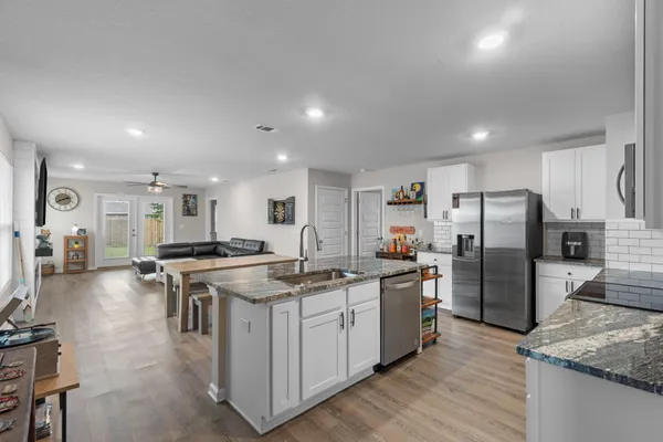 a kitchen with stainless steel appliances kitchen island granite countertop a refrigerator and a sink
