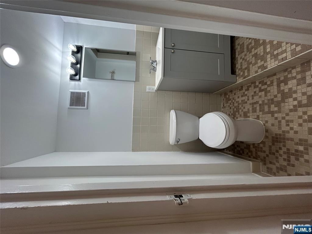 109 Grand Avenue, Unit 1A Englewood, NJ 07631 - Photo 23 of 25 a bathroom with a toilet sink and mirror