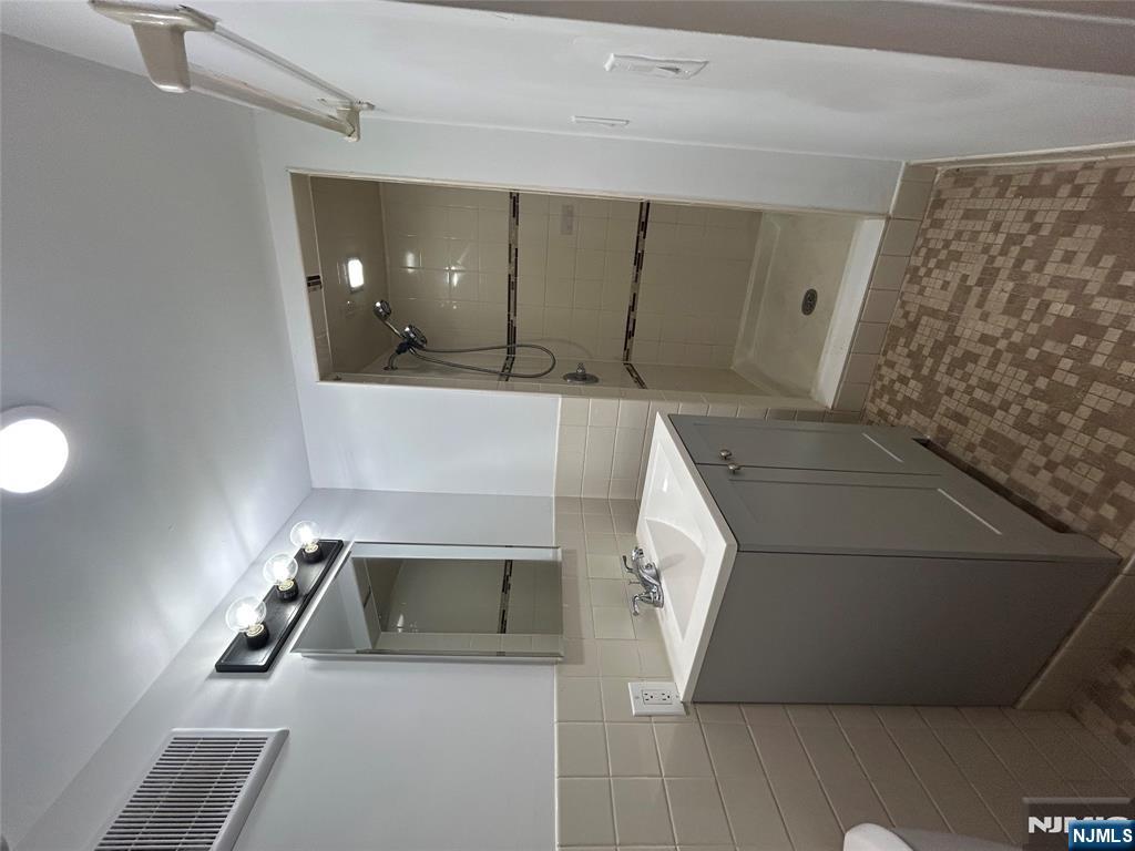 109 Grand Avenue, Unit 1A Englewood, NJ 07631 - Photo 24 of 25 a bathroom with a sink a shower and mirror