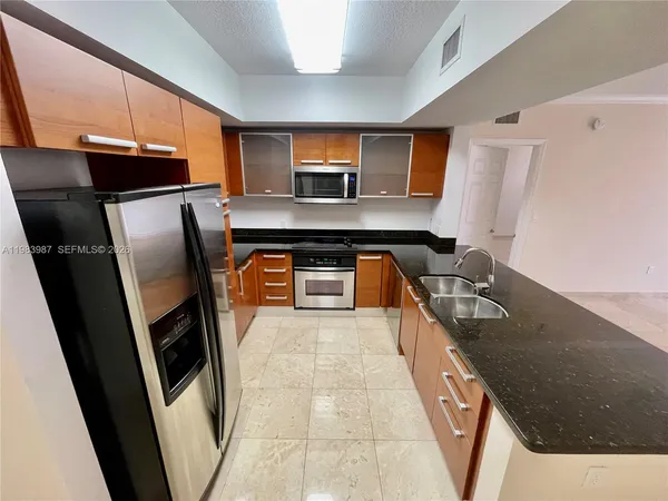 a kitchen with stainless steel appliances granite countertop a refrigerator a stove and a sink