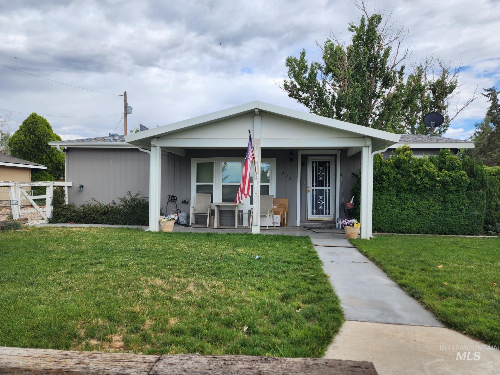 235 5th Street Grand View, ID 83624 - Photo 1 of 22 Front exterior featuring a covered porch, established lawn, concrete pathway, and mature landscaping