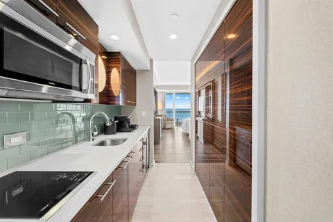 a kitchen with stainless steel appliances a sink a stove top oven a chimney and a center island