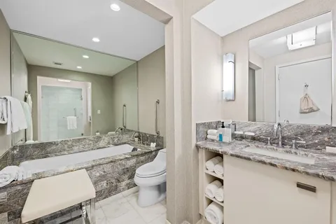 a bathroom with a granite countertop sink mirror and toilet