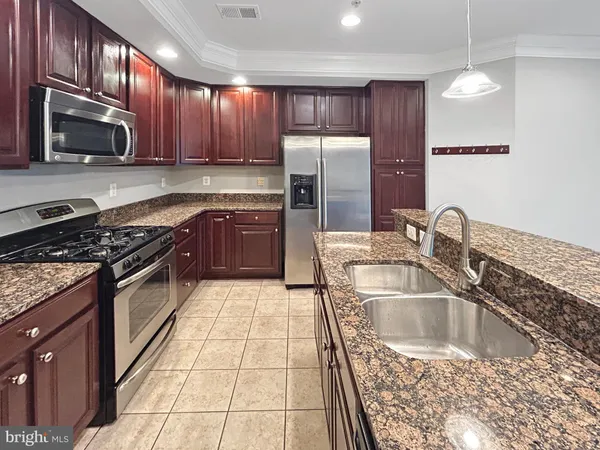 a kitchen with granite countertop a sink a stove top oven and refrigerator