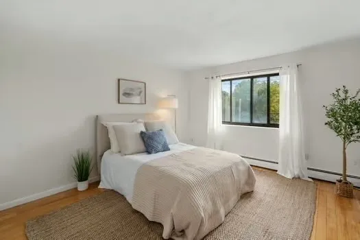 a large bed sitting in a bedroom next to a window and a wooden floor