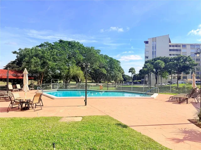 a view of swimming pool with lawn chairs and plants