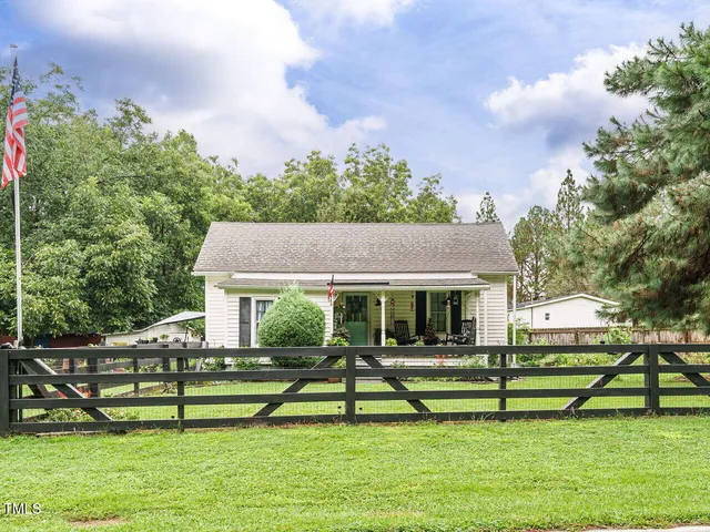 a house view with a garden space and wooden fence