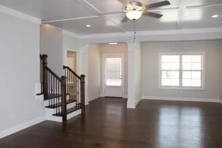 an empty room with wooden floor fan and windows