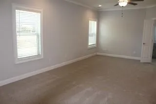 an empty room with windows and chandelier fan