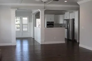 a view of kitchen with stainless steel appliances wooden floors and view living room