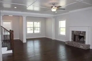 an empty room with wooden floor fireplace and windows