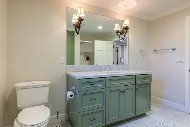 a bathroom with a granite countertop toilet sink and mirror