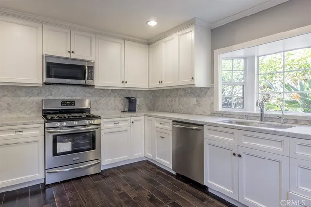 a kitchen with cabinets stainless steel appliances a sink and a window