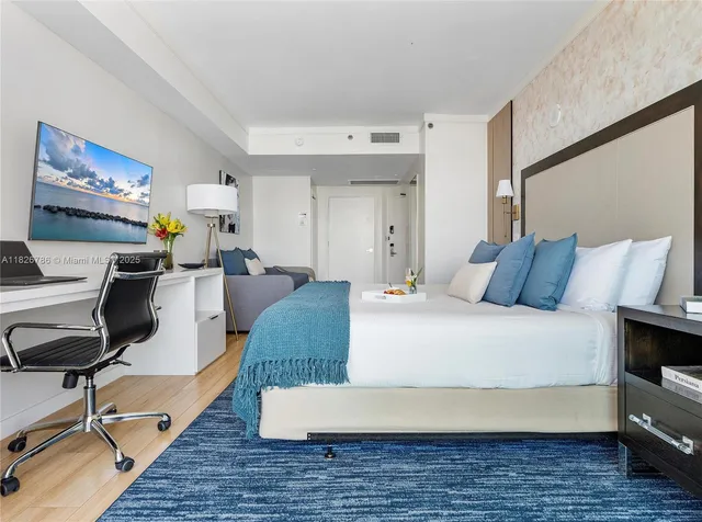 a spacious bedroom with a bed a couch and large window with balcony view