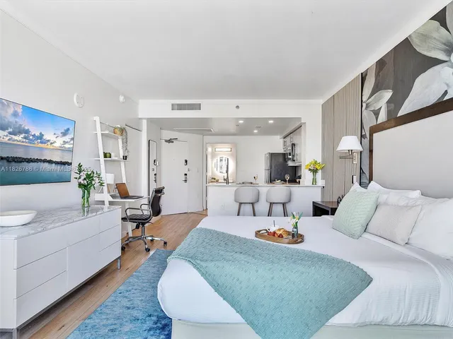 a bedroom with a bed a large window and a potted plant on the table