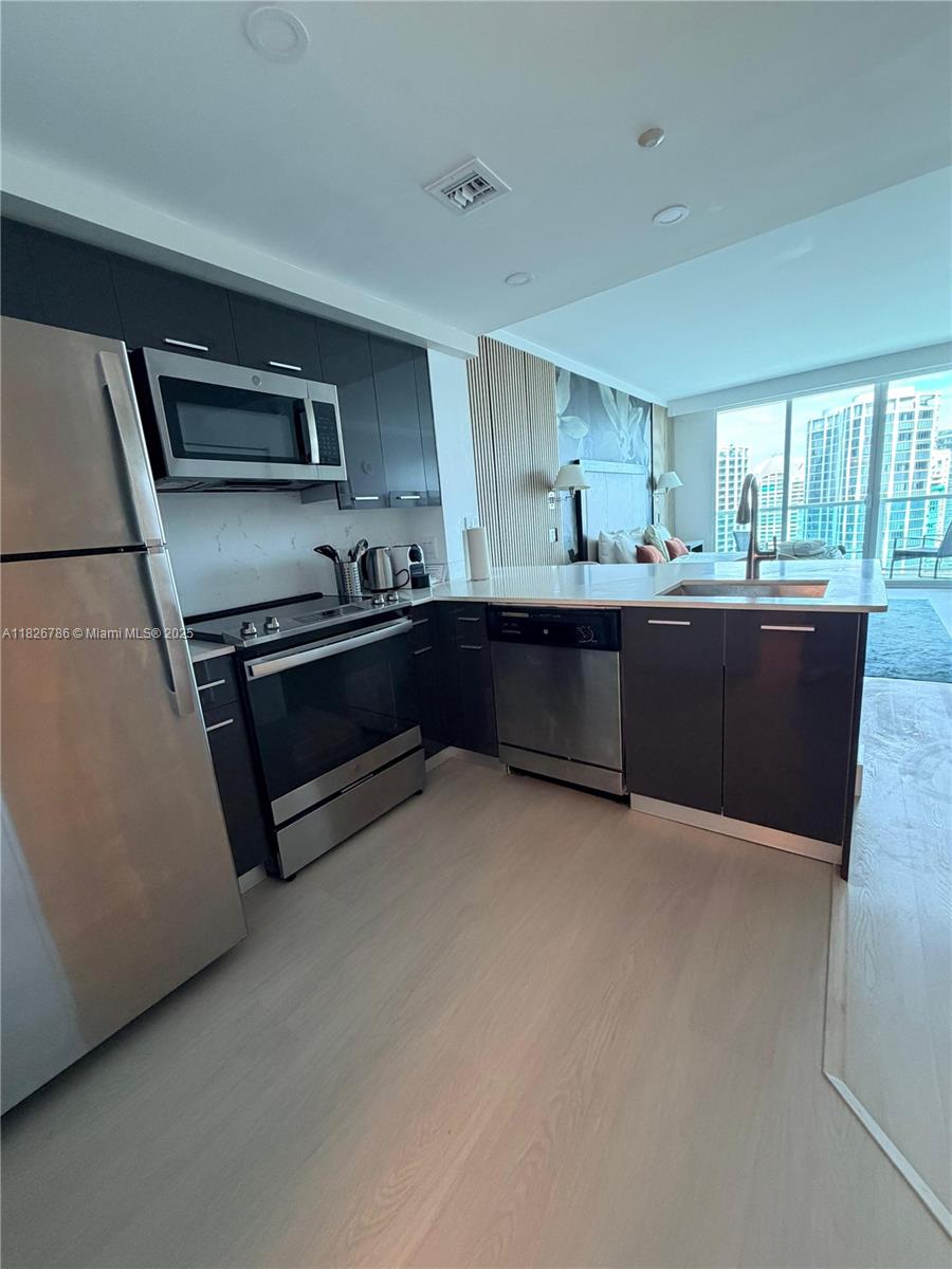 2889 McFarlane Road, Unit 1908 Miami, FL 33133 - Photo 8 of 26 a kitchen with stainless steel appliances granite countertop a stove a sink and a refrigerator
