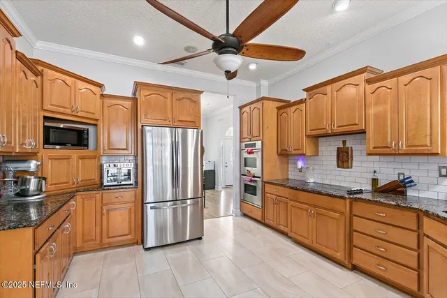 a large kitchen with stainless steel appliances granite countertop a refrigerator a sink dishwasher a stove and white countertops with wooden floor