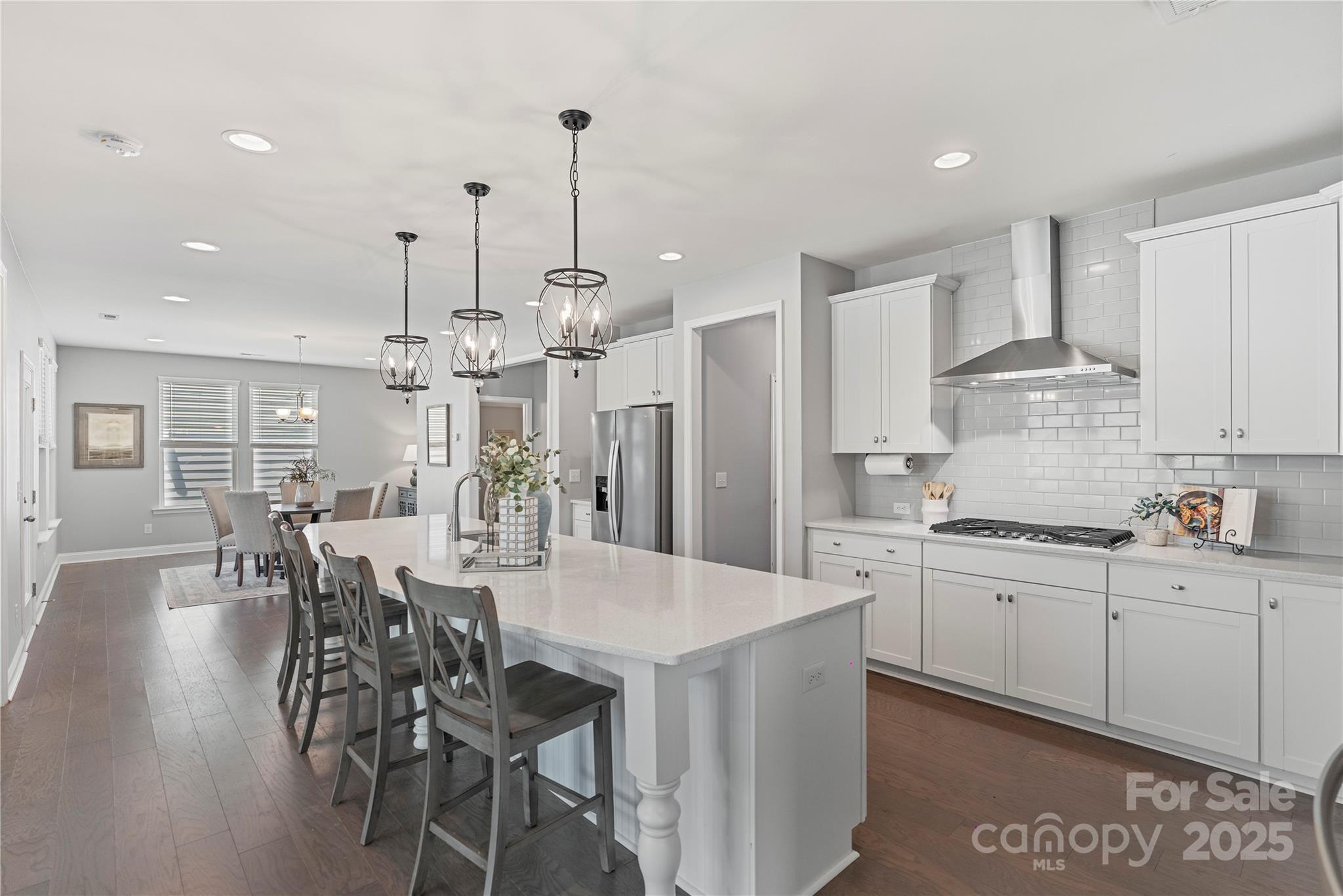 a large kitchen with kitchen island a dining table chairs and white cabinets