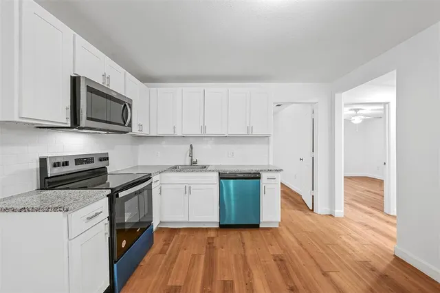 a kitchen with stainless steel appliances granite countertop a stove top oven a sink dishwasher and a refrigerator