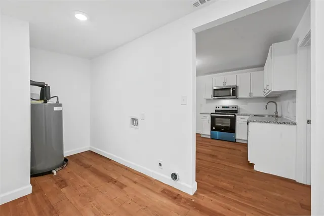 a kitchen with wooden floor and electronic appliances