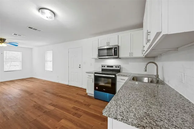 a kitchen with granite countertop a stove a sink and a microwave