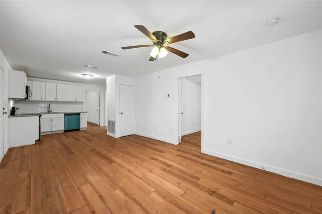 a view of empty room with wooden floor and ceiling fan