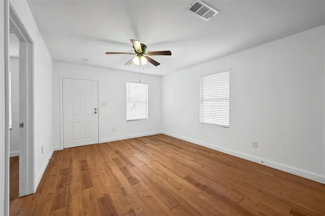 a view of empty room with wooden floor and fan
