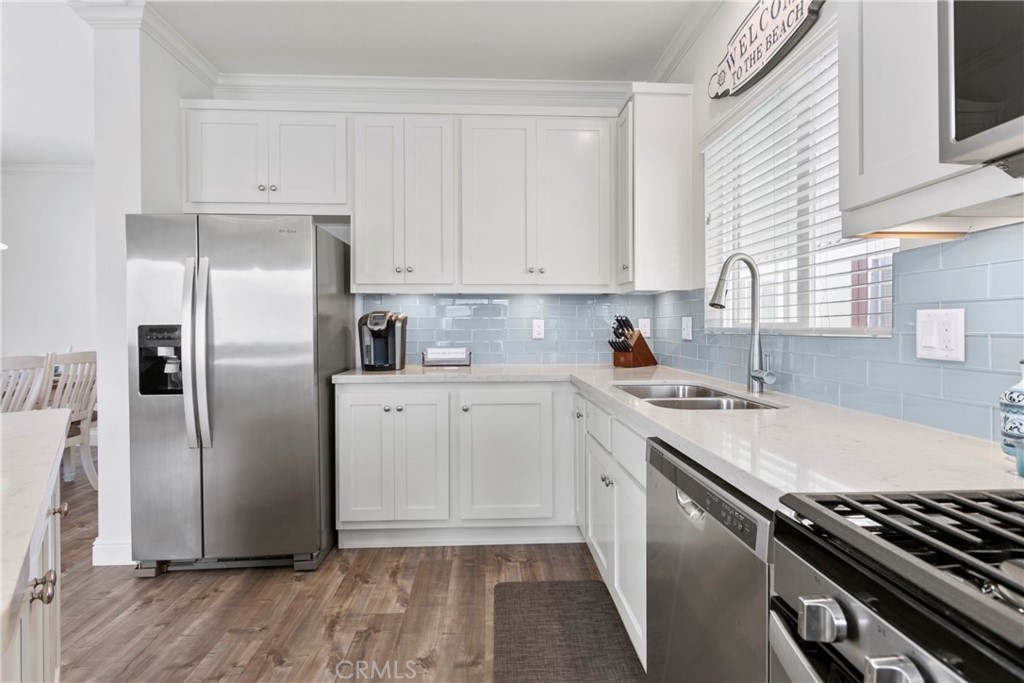 108 Bay Drive San Clemente, CA 92672 - Photo 21 of 28 a kitchen with stainless steel appliances granite countertop a refrigerator a sink dishwasher a stove and white countertops with wooden floor