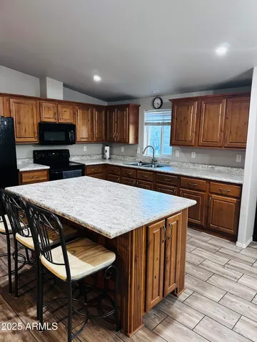 a kitchen with stainless steel appliances kitchen island granite countertop a table chairs sink and cabinets