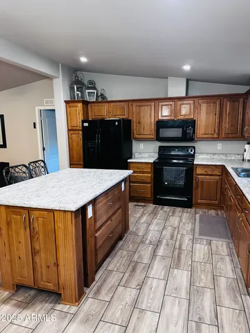 a kitchen with stainless steel appliances kitchen island granite countertop a refrigerator and a stove top oven