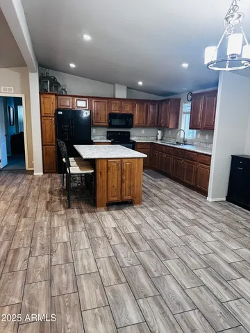 a kitchen with stainless steel appliances kitchen island granite countertop a table chairs sink and cabinets