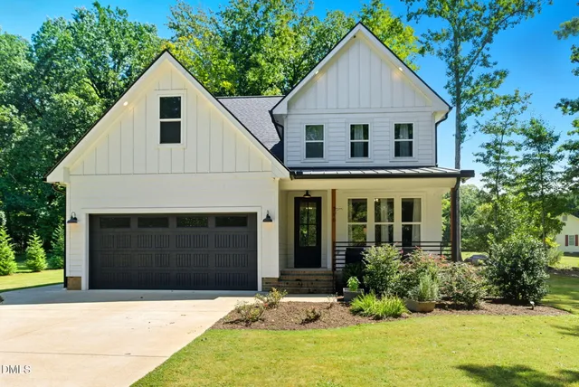 a view of a white house with large windows and plants