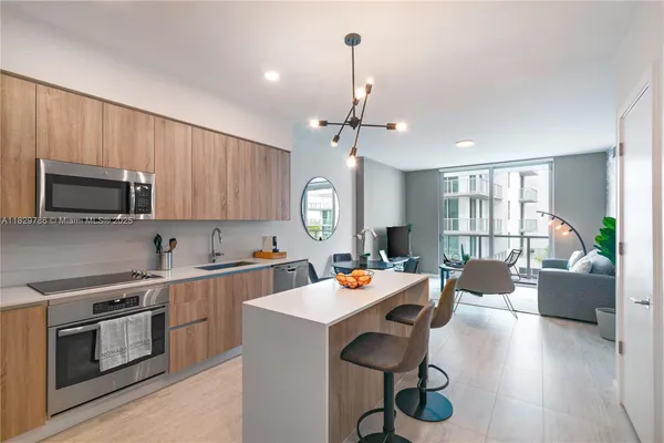 a open kitchen with stainless steel appliances granite countertop a stove top oven a refrigerator a sink dishwasher a dining table and chairs with wooden floor