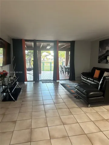 a living room with furniture a flat screen tv and a floor to ceiling window