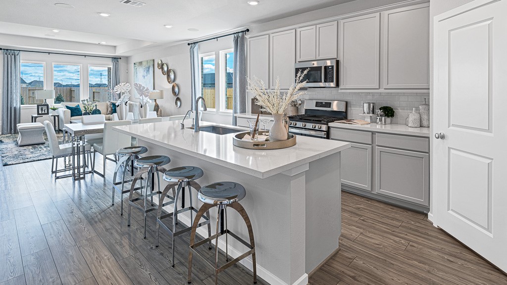 1202 Buffalo Run Tomball, TX 77375 - Photo 11 of 45 a kitchen with stainless steel appliances granite countertop white cabinets a stove a sink and a wooden floor
