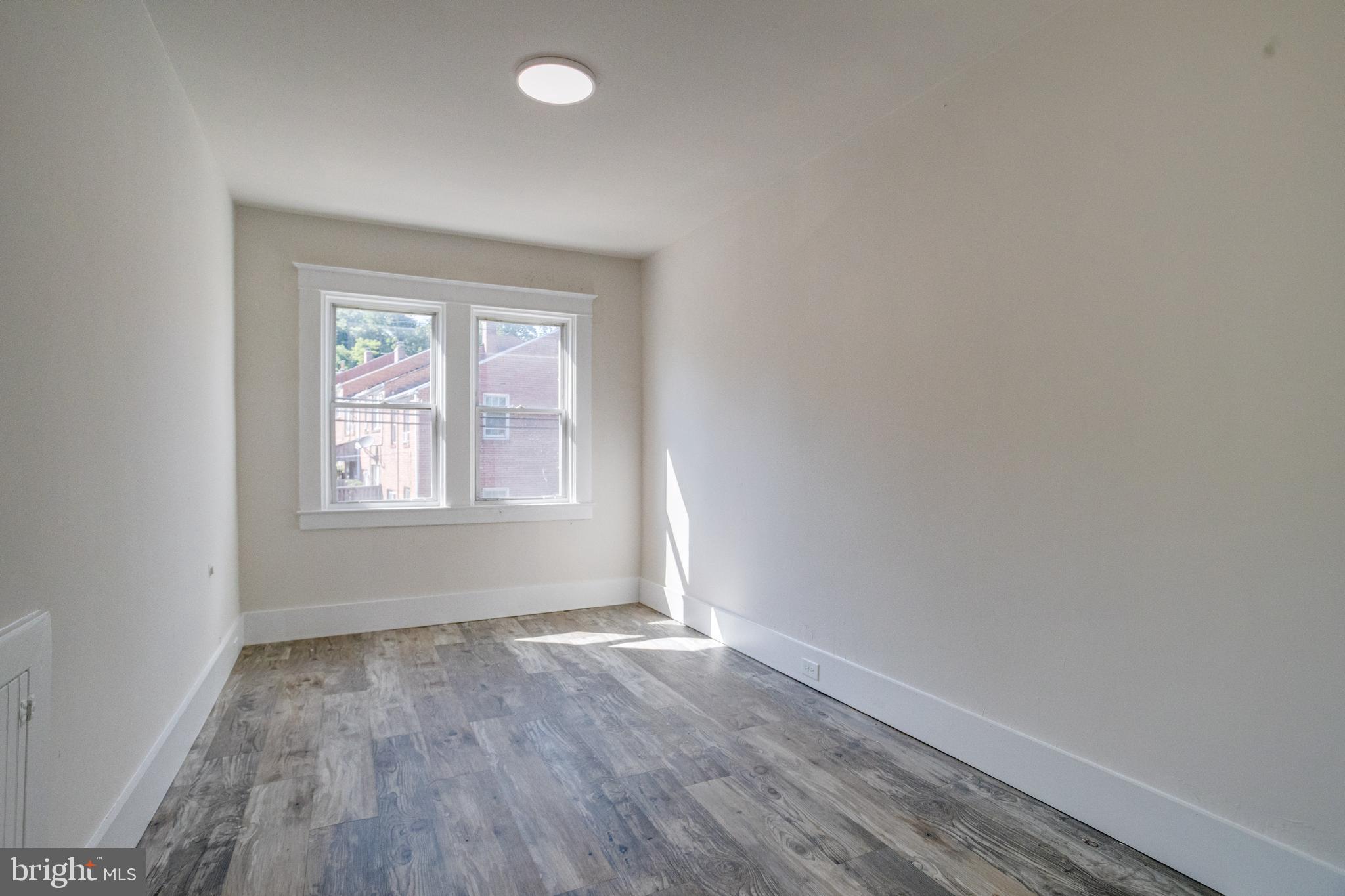 5878 Belair Road Baltimore, MD 21206 - Photo 24 of 41 an empty room with wooden floor and windows