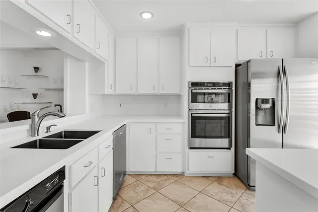 a kitchen with white cabinets and stainless steel appliances
