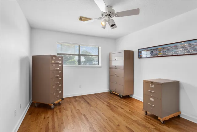 an empty room with wooden floor cabinet and windows
